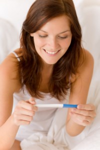 A happy surprised woman reading the results of a home pregnancy test